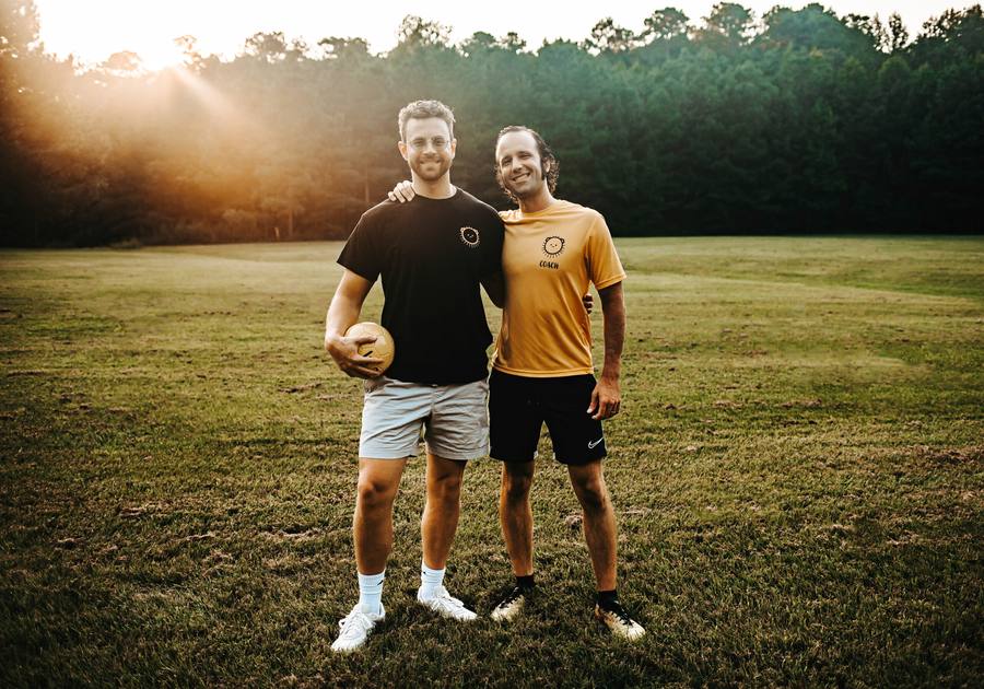 Coach PJ and Coach Chris on the field at golden hour