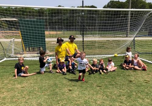A Little Lions class hanging out under the goal with their coaches