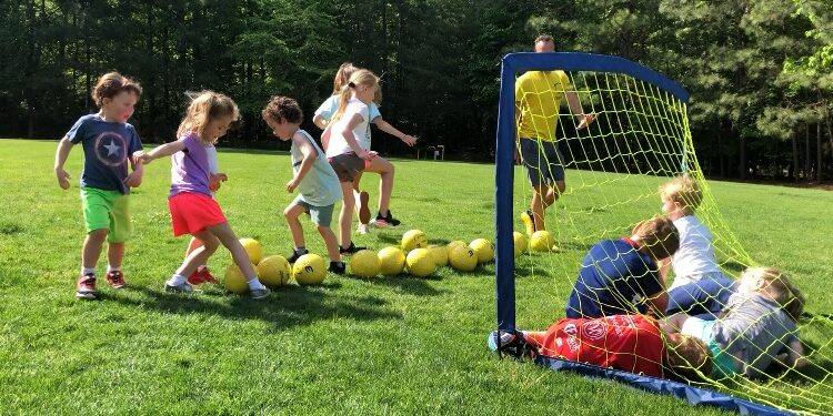 Kids dribbling toward a small goal at a partner school