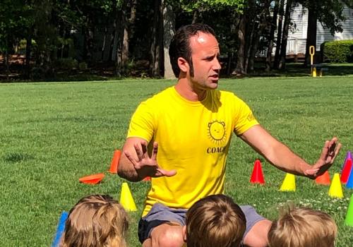 Coach PJ mid-story with a circle of young players